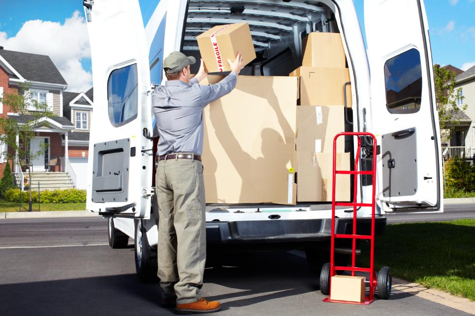 A man in uniform loading unmarked boxes of different sizes in to a van